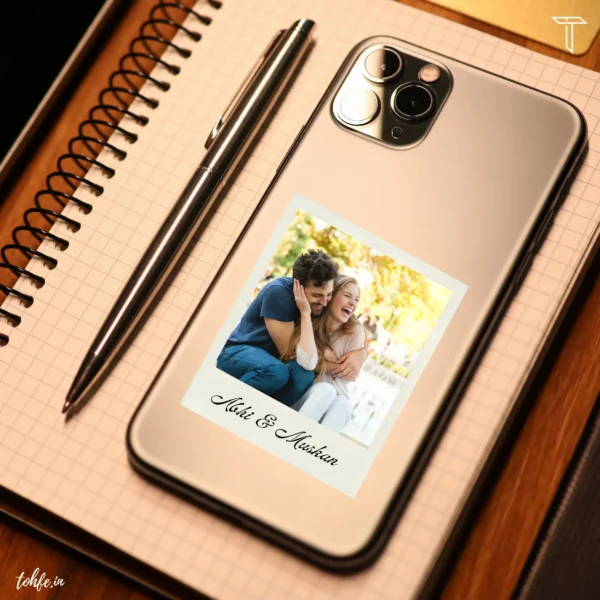 mobile back cover with couple photo name written abhi & muskan on iphone 13 pro along a pen and diary